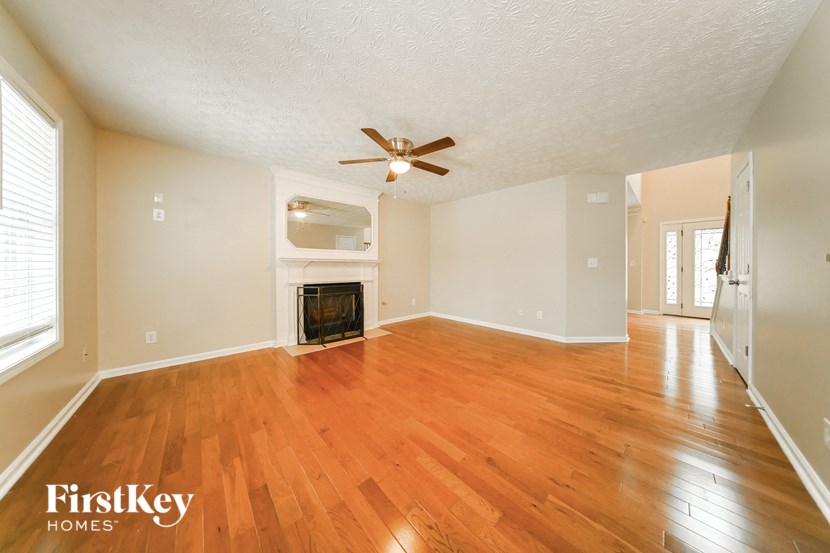 an empty living room with a fireplace and wooden floors