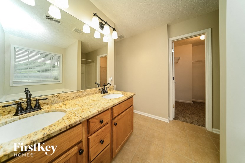 the master bathroom has dual sinks and a large mirror