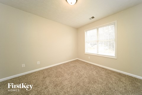 the upstairs bedroom has carpet and a large window