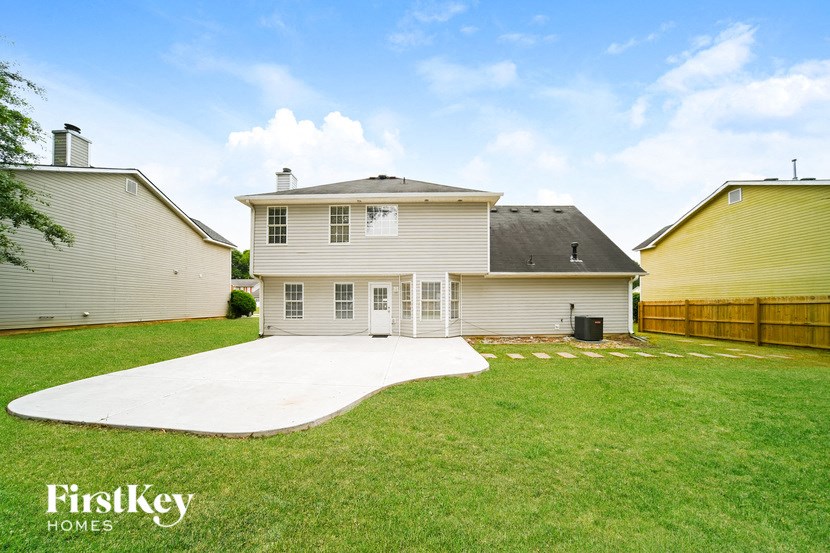 a backyard with a white house and a concrete driveway