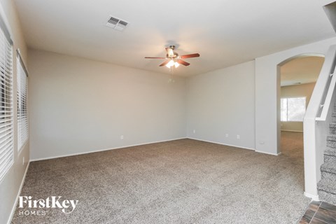 A spacious room with a ceiling fan and carpeted floor.