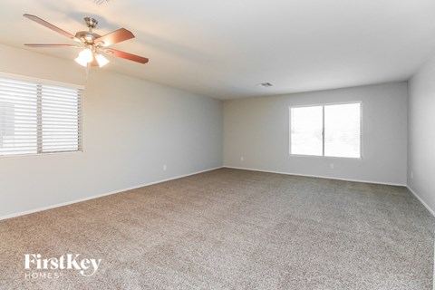 A room with a ceiling fan and carpeted floor.