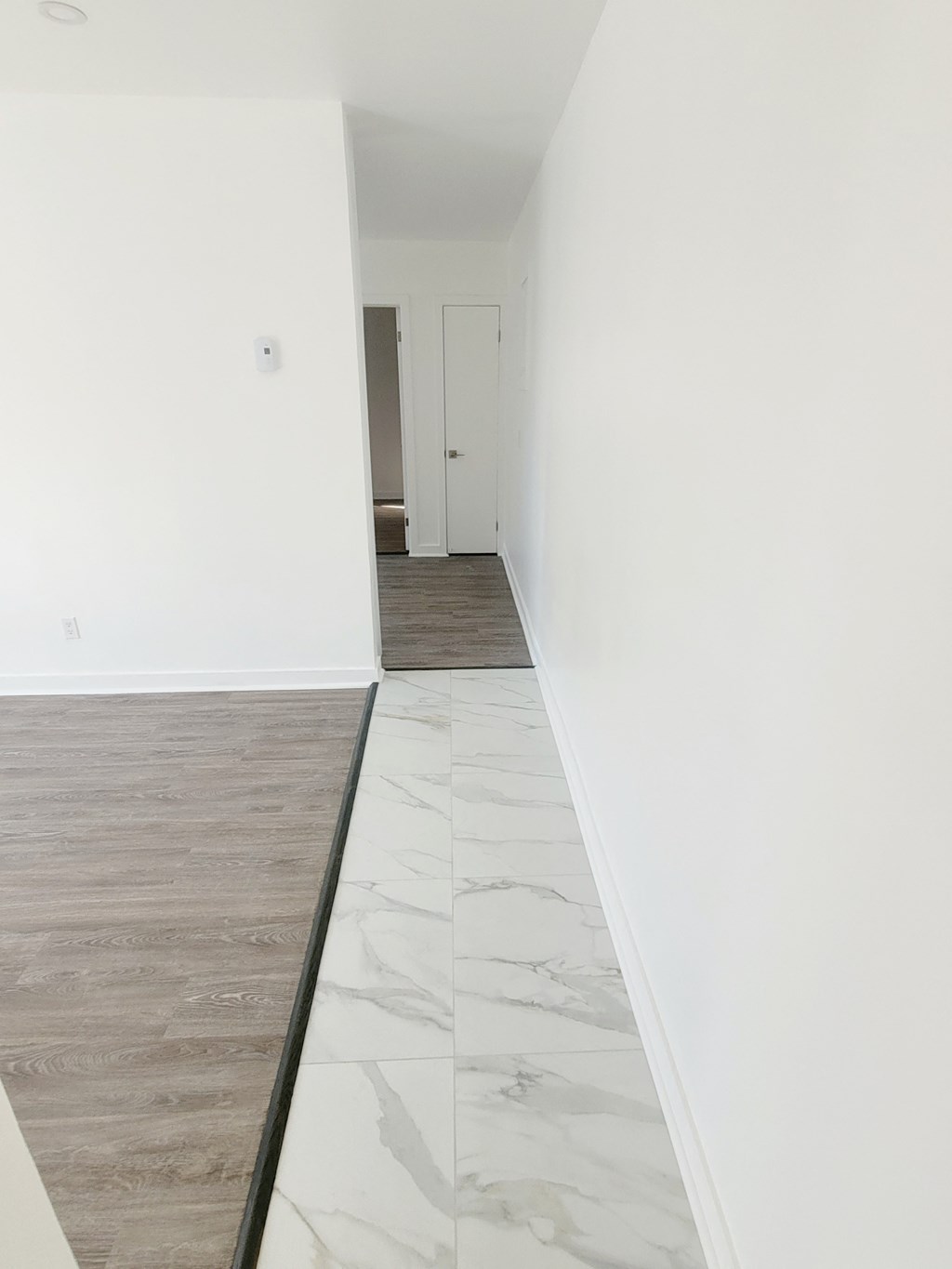 an empty room with white walls and white marble floors and a white door