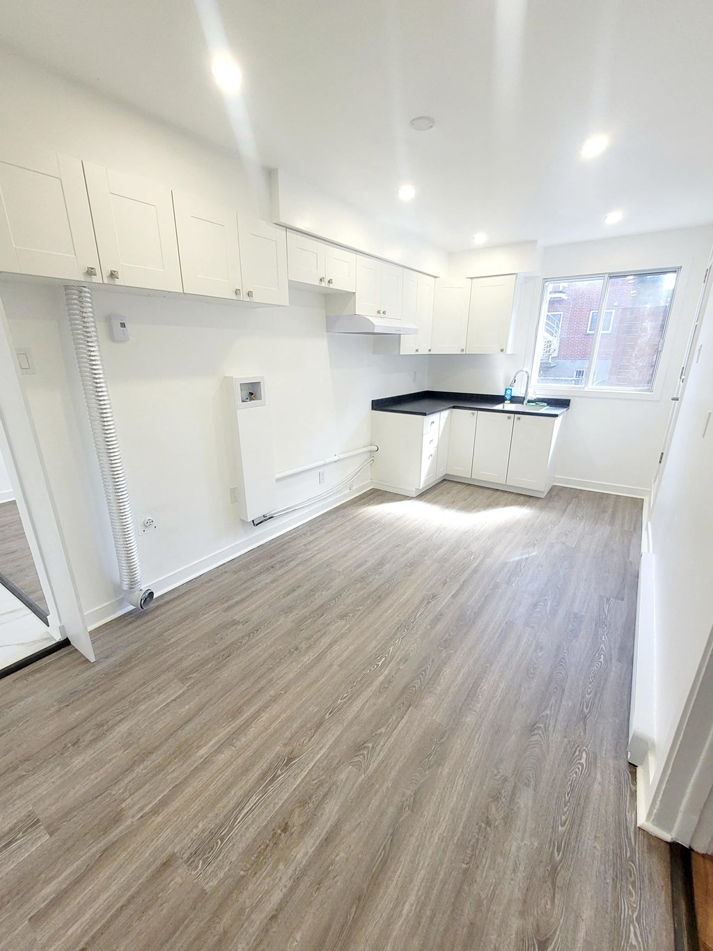 an empty kitchen with white cabinets and a wood floor