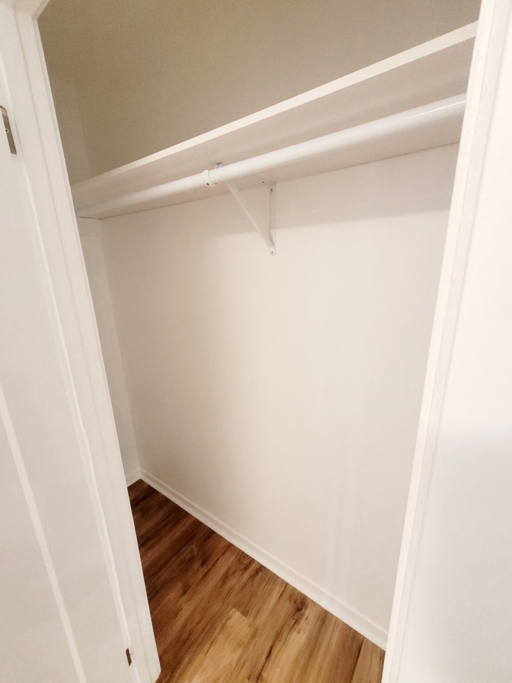 an empty closet with a wooden floor and white walls