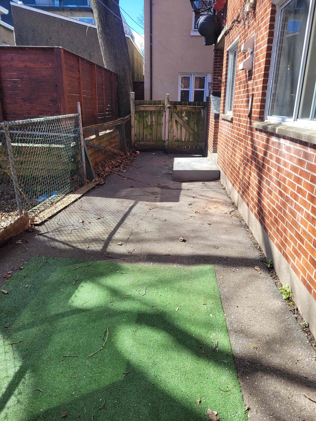 a backyard patio with a brick building and a wooden fence