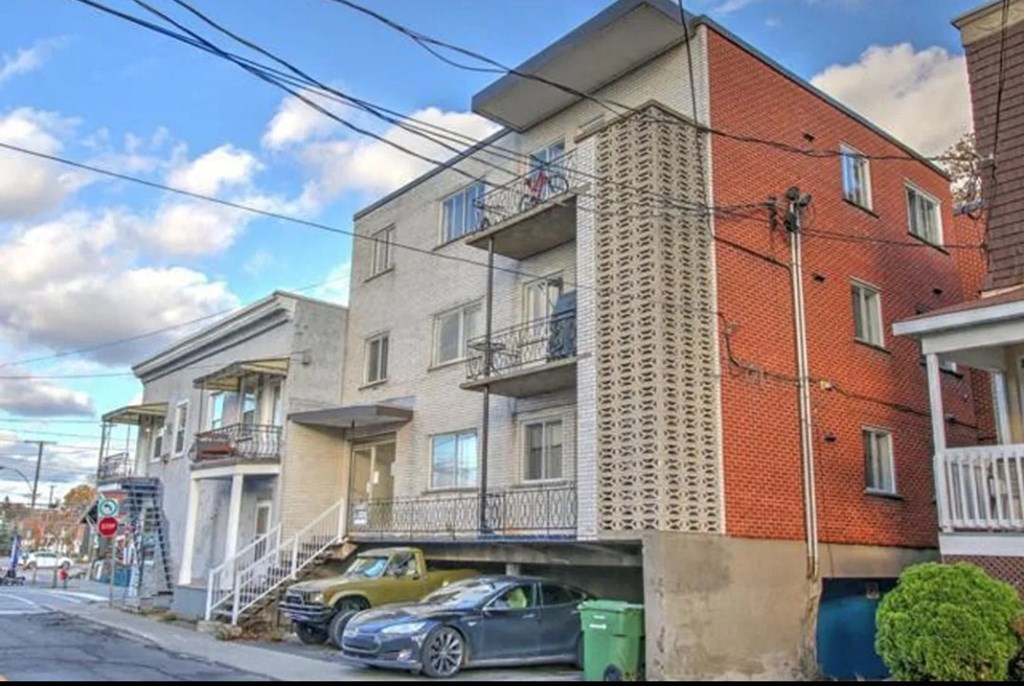 the apartment building has two cars parked underneath it