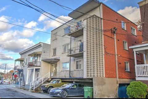 the apartment building has two cars parked underneath it