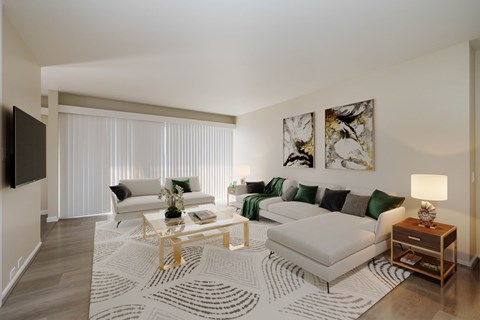 A living room with a white couch, a coffee table, and a television on the wall.