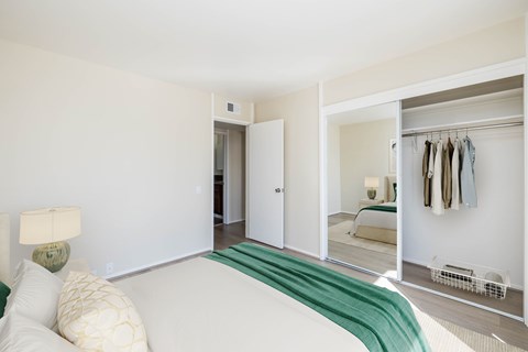 A bedroom with a bed, a lamp, and a closet.