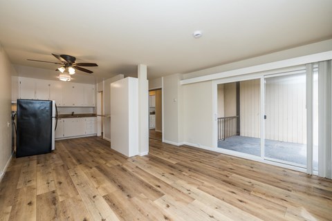 A spacious room with wooden flooring and a ceiling fan.