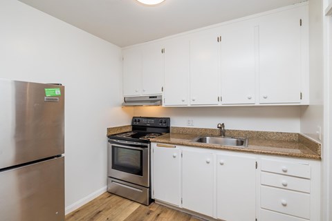 A kitchen with white cabinets and a stainless steel refrigerator.