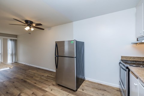 A kitchen with a stainless steel refrigerator and wooden flooring.