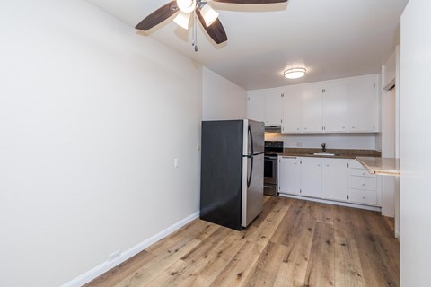 A kitchen with a black refrigerator and wooden floors.