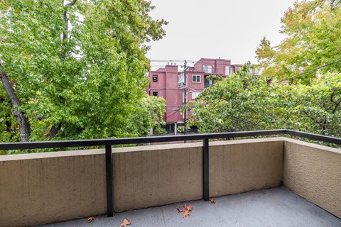 a balcony with trees and a pink building in the background
