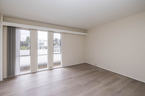 an empty living room with sliding glass doors and wood floors