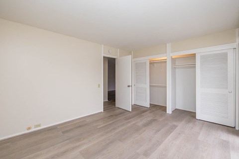 a bedroom with white walls and doors and a wood floor