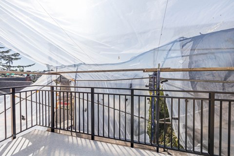 A construction site covered with a white tarp and a black fence.