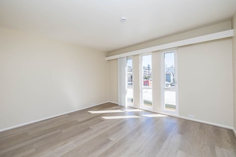 A room with wooden flooring and sliding glass doors.