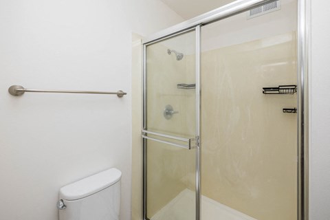 A white toilet sits next to a glass shower door.