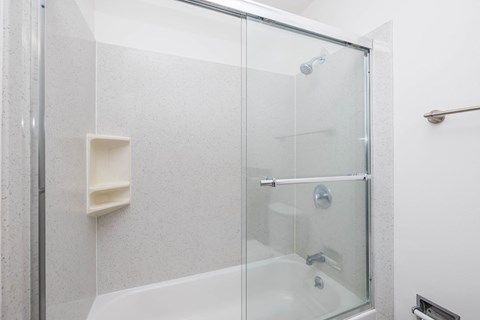 A white shower stall with a glass door and a white soap holder.