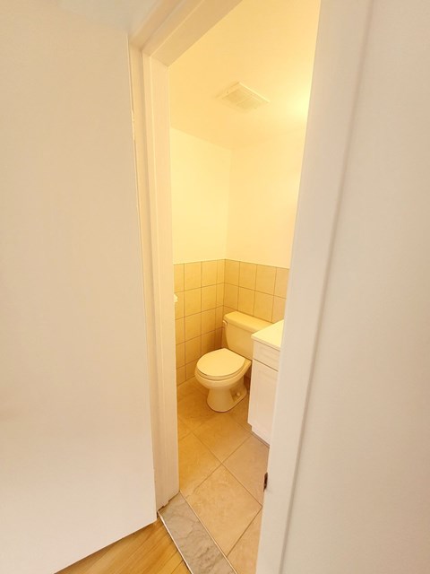 A small bathroom with a toilet and a tiled wall.