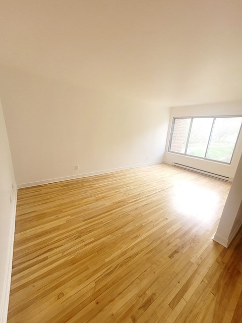 A room with wooden flooring and a window letting in light.