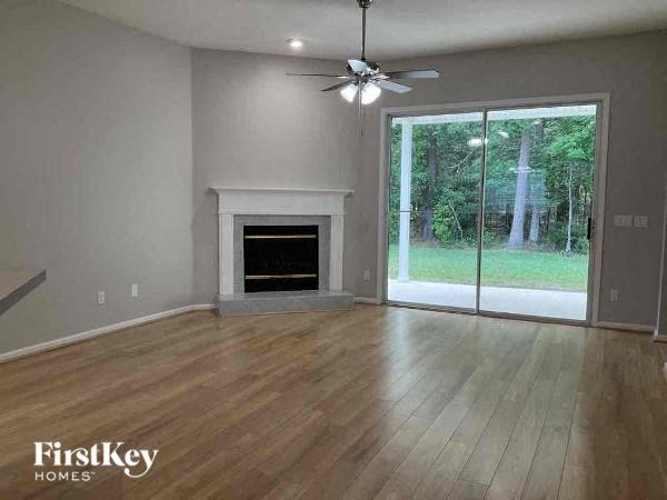 an empty living room with a fireplace and a ceiling fan