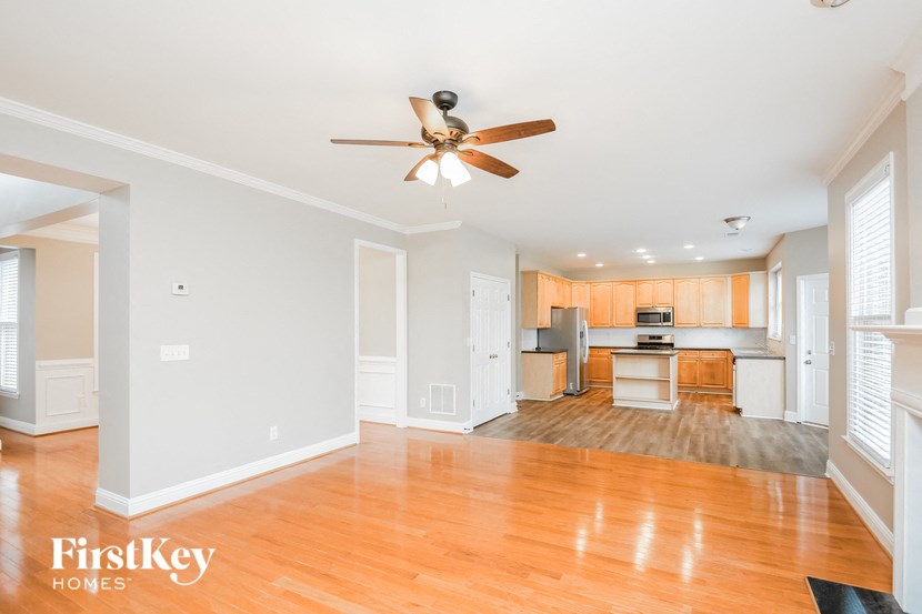 an empty living room and kitchen with wood floors and a ceiling fan