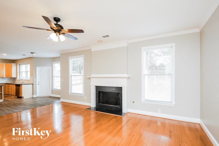 an empty living room with a fireplace and a ceiling fan