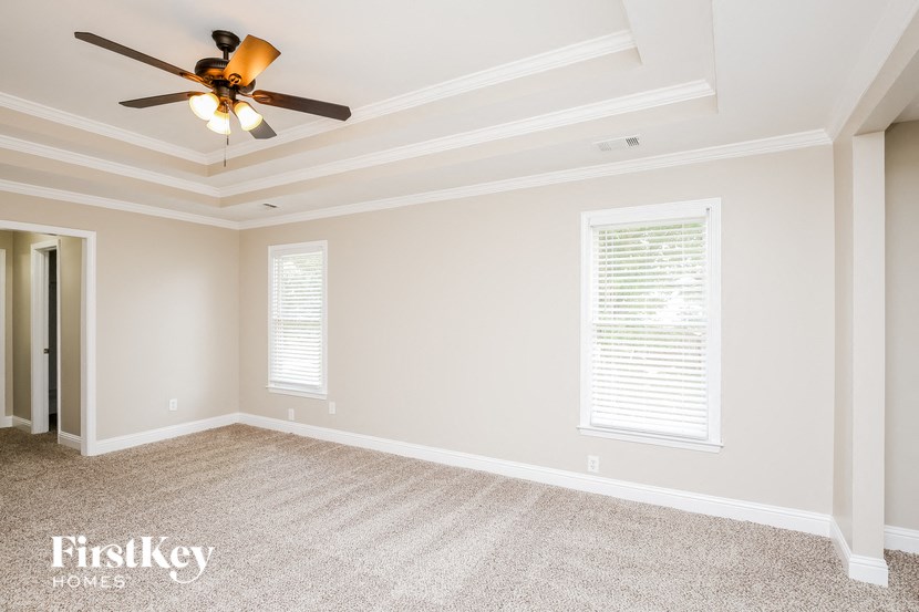a empty living room with a ceiling fan and window