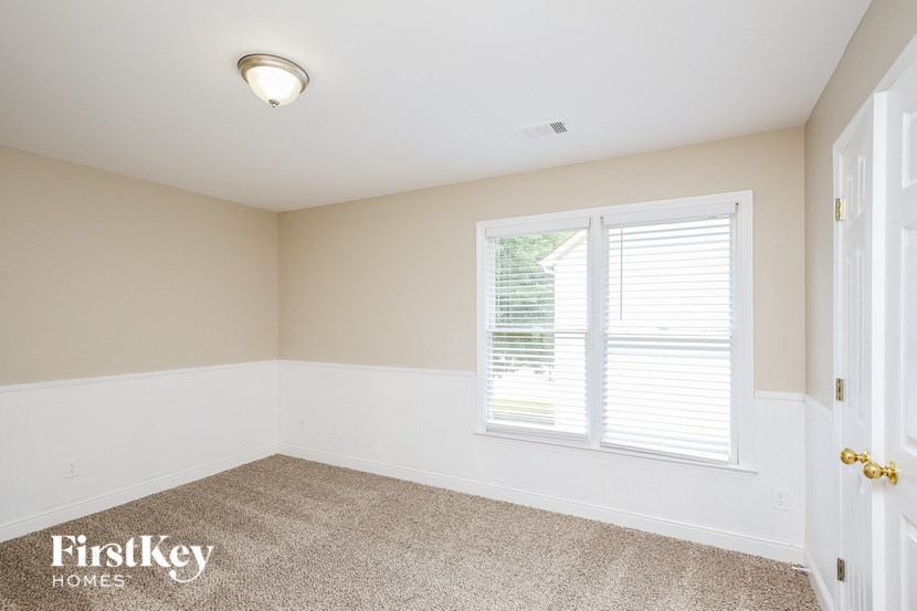 a bedroom with a large window and a carpeted floor