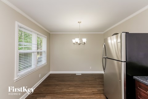 A kitchen with a stainless steel refrigerator and wooden flooring.