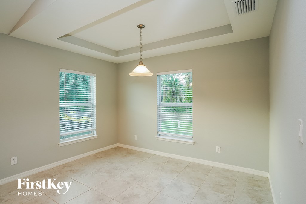 an empty dining room with two windows and a ceiling light