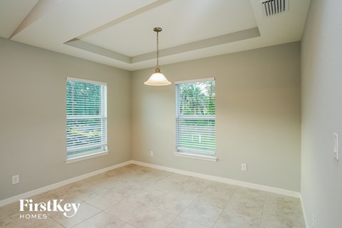 an empty dining room with two windows and a ceiling light