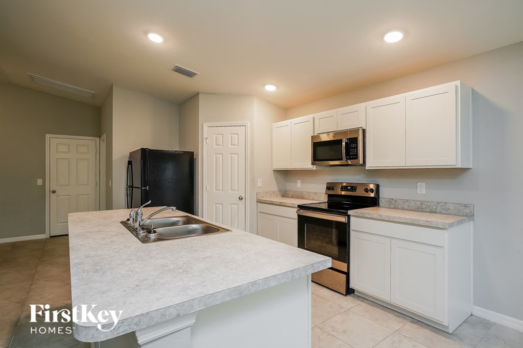 a kitchen with white cabinets and black appliances and a sink