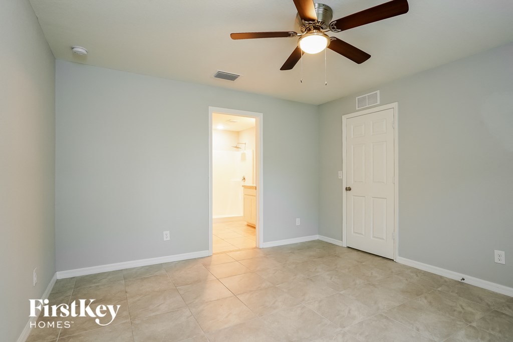 a empty room with a ceiling fan and a door to a bathroom