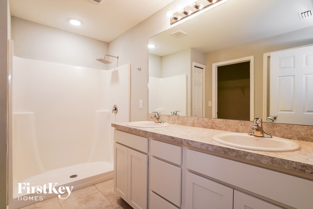 a bathroom with two sinks and a shower and a mirror