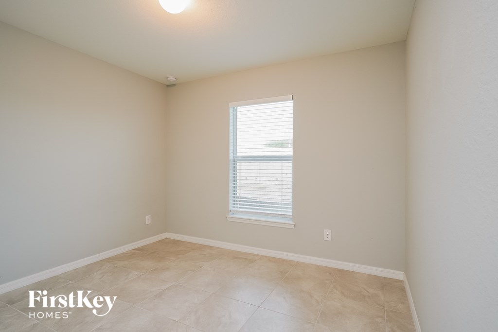 the second bedroom has a large window and tiled floors