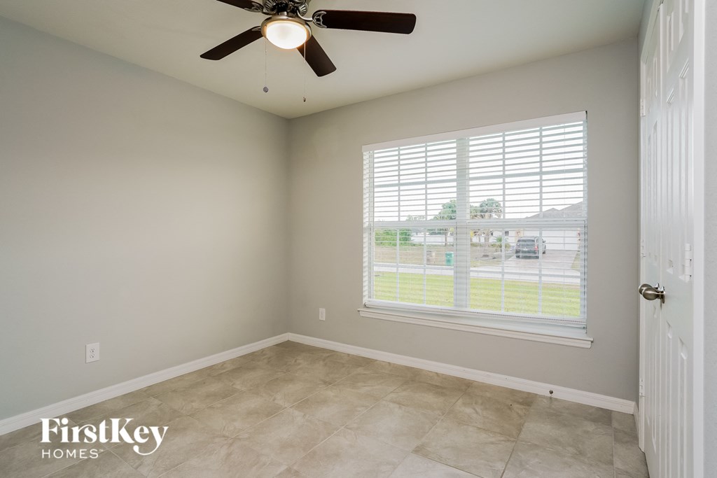 an empty room with a large window and a ceiling fan