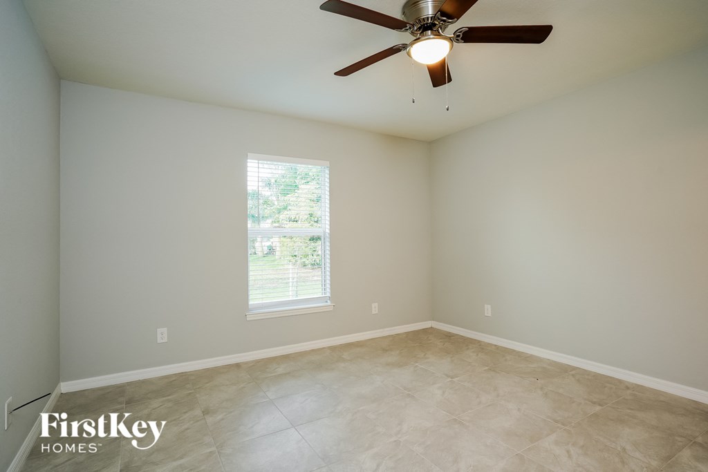 an empty room with a ceiling fan and a window
