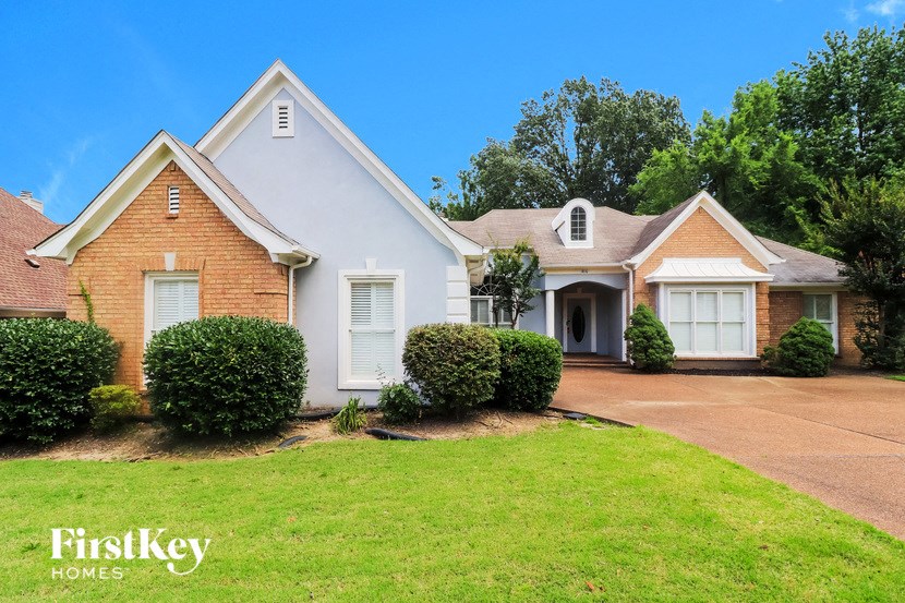a white and brick house with a lawn and a driveway