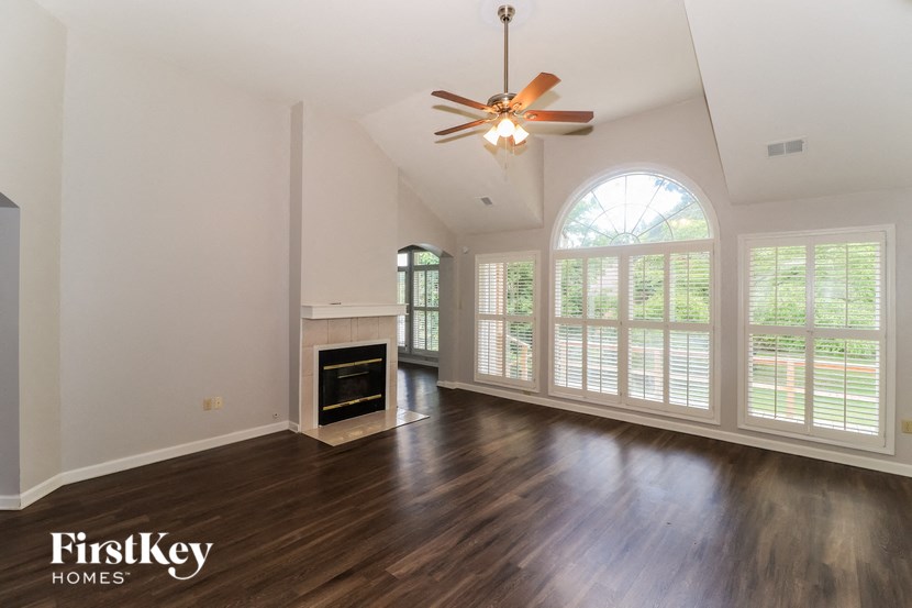 an empty living room with a large window and a ceiling fan
