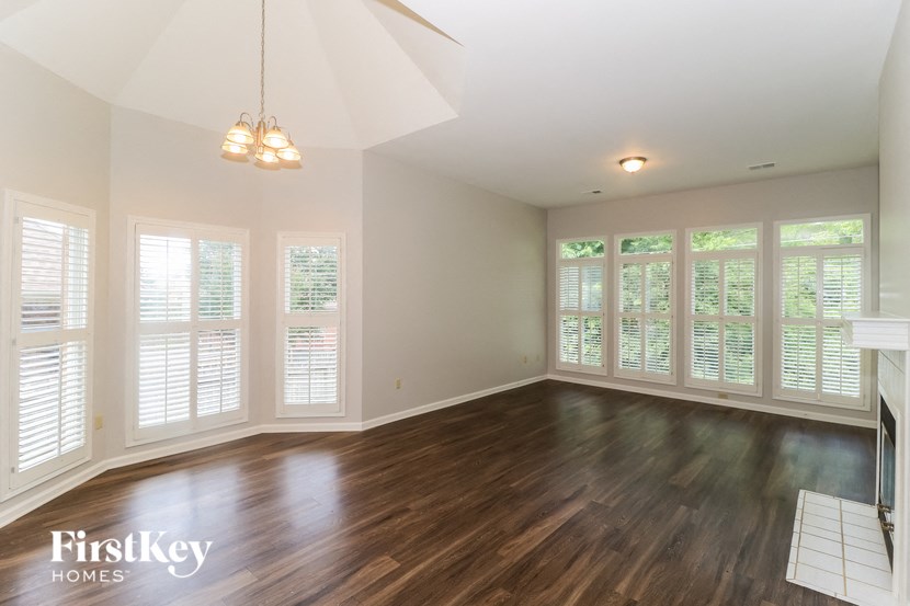 an empty living room with wood flooring and large windows