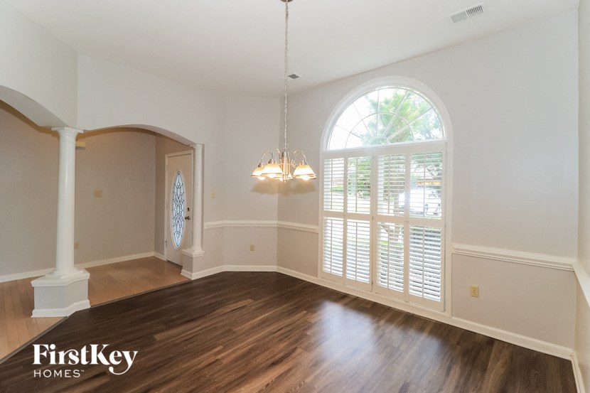 an empty living room with a large arched window and wooden floors