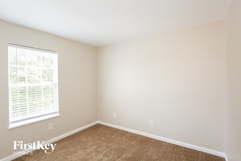 a bedroom with a large window and brown carpet