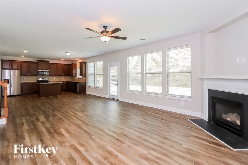 an empty living room with a fireplace and a kitchen