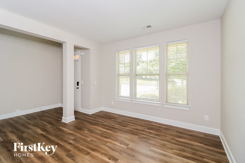 the living room of a home with wood flooring and white walls
