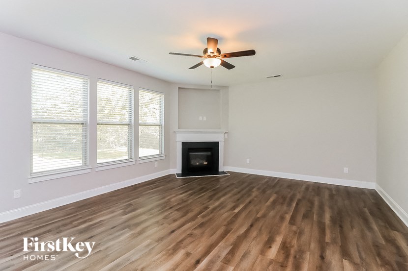 an empty living room with a ceiling fan and a fireplace