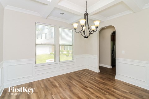 an empty dining room with a chandelier and a window